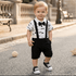 Child wearing a black and white outfit with suspenders and a bow tie on a street.