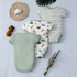 Three baby bodysuits with different patterns on a textured surface.