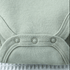 Close-up of a light green baby romper with button details on a textured fabric background.