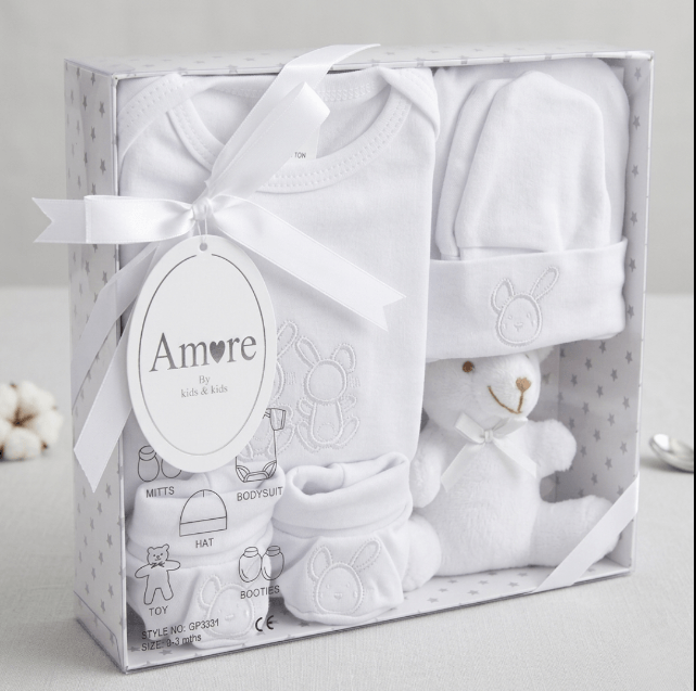 Baby gift set with white baby clothes and a toy in a box labeled 'Amore'.
