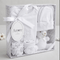 Baby gift set with white baby clothes and a toy in a box labeled 'Amore'.