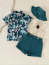 Children's outfit with leaf-patterned shirt, shorts, suspenders, and hat on a beige background