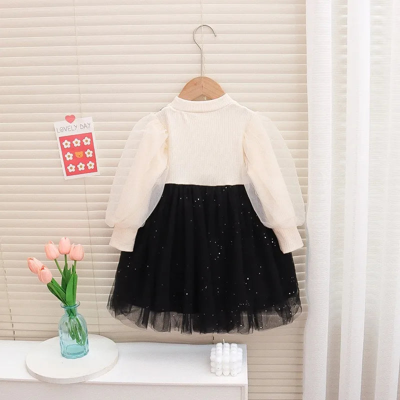 White long-sleeve top and black tulle skirt set on a hanger against a neutral background.