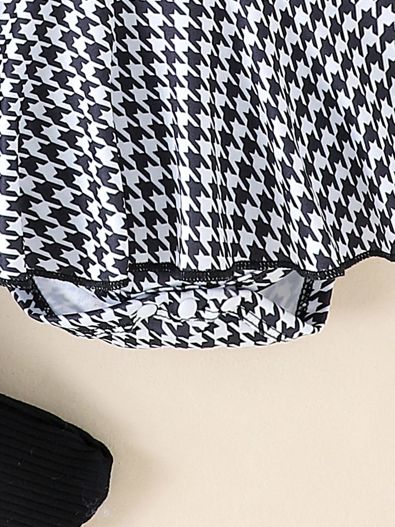 Close-up of a black and white houndstooth patterned fabric on a beige background