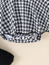 Close-up of a black and white houndstooth patterned fabric on a beige background