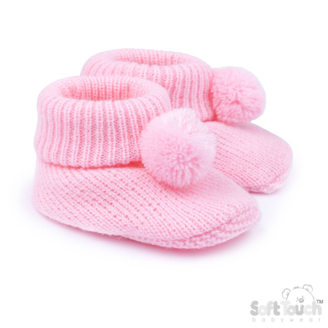 A pair of light pink knit baby booties with matching pom-poms, shown on a clean white background with a Soft Touch Babywear logo in the bottom right corner.