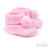 A pair of light pink knit baby booties with matching pom-poms, shown on a clean white background with a Soft Touch Babywear logo in the bottom right corner.