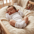 Newborn baby sleeping in a crib with a teddy bear and British flag-themed toy.