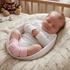 Newborn baby sleeping in a white crib with pink leg warmers, surrounded by toys.