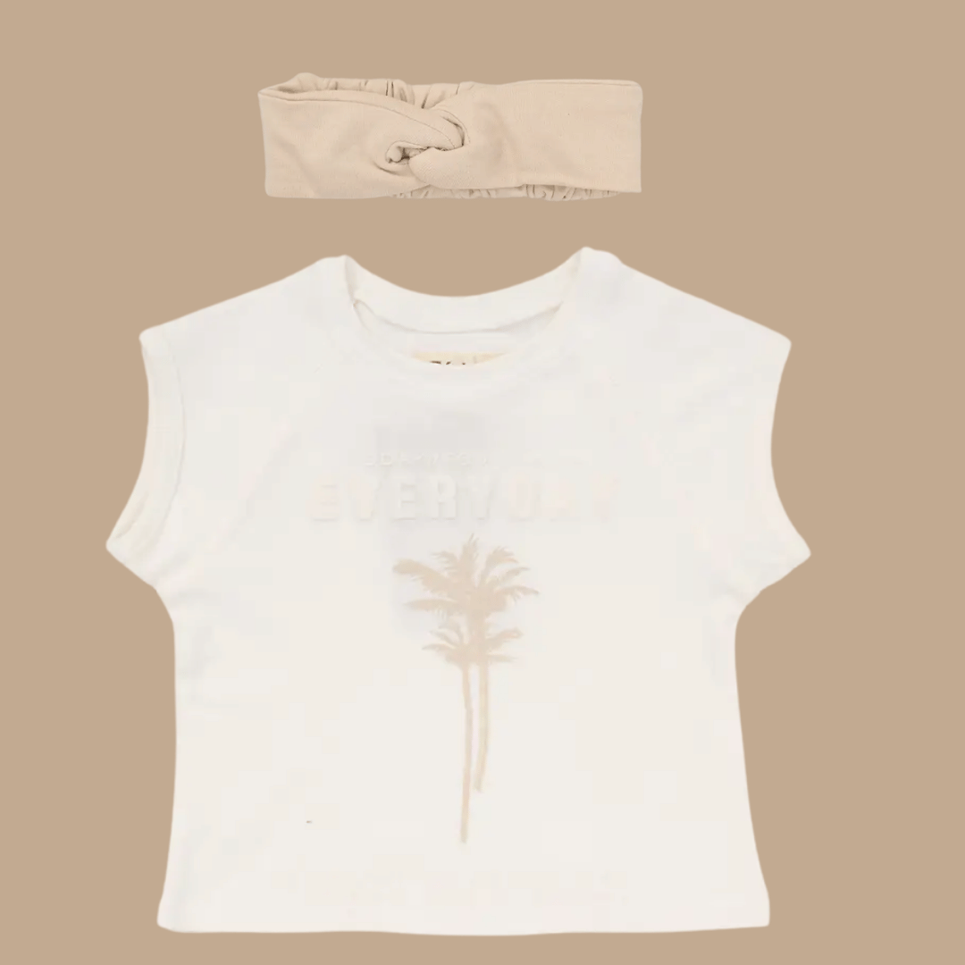 White sleeveless top with palm tree design and beige headband on a beige background