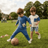Two children playing with a soccer ball on a grassy field.