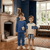 Two children standing in a room with a fireplace and large window.