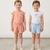 Two young girls wearing matching outfits with floral patterns on a plain background