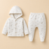 A baby two-piece outfit set featuring a hooded button-front cardigan and matching footed pants, both in a soft off-white ribbed fabric with a subtle light beige animal print, displayed on a solid beige background.