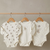 Three baby bodysuits with bear patterns on wooden hangers against a neutral background