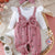Baby outfit with pink romper and white shirt on a textured surface with flowers and a basket.