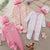 Collection of baby clothing and accessories on a neutral background with flowers.