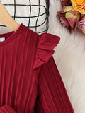 Red ribbed sweater with ruffled shoulders on a white surface with flowers.