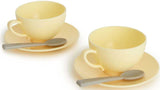 Set of yellow ceramic cups and saucers with spoons on a white background