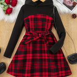 Black hoodie with a red plaid dress on a wooden surface with decorative items.