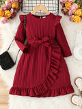 Red dress with ruffled details on a hanger against a floral and textured background
