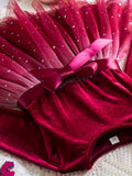 Red velvet outfit with a pink bow on a textured surface