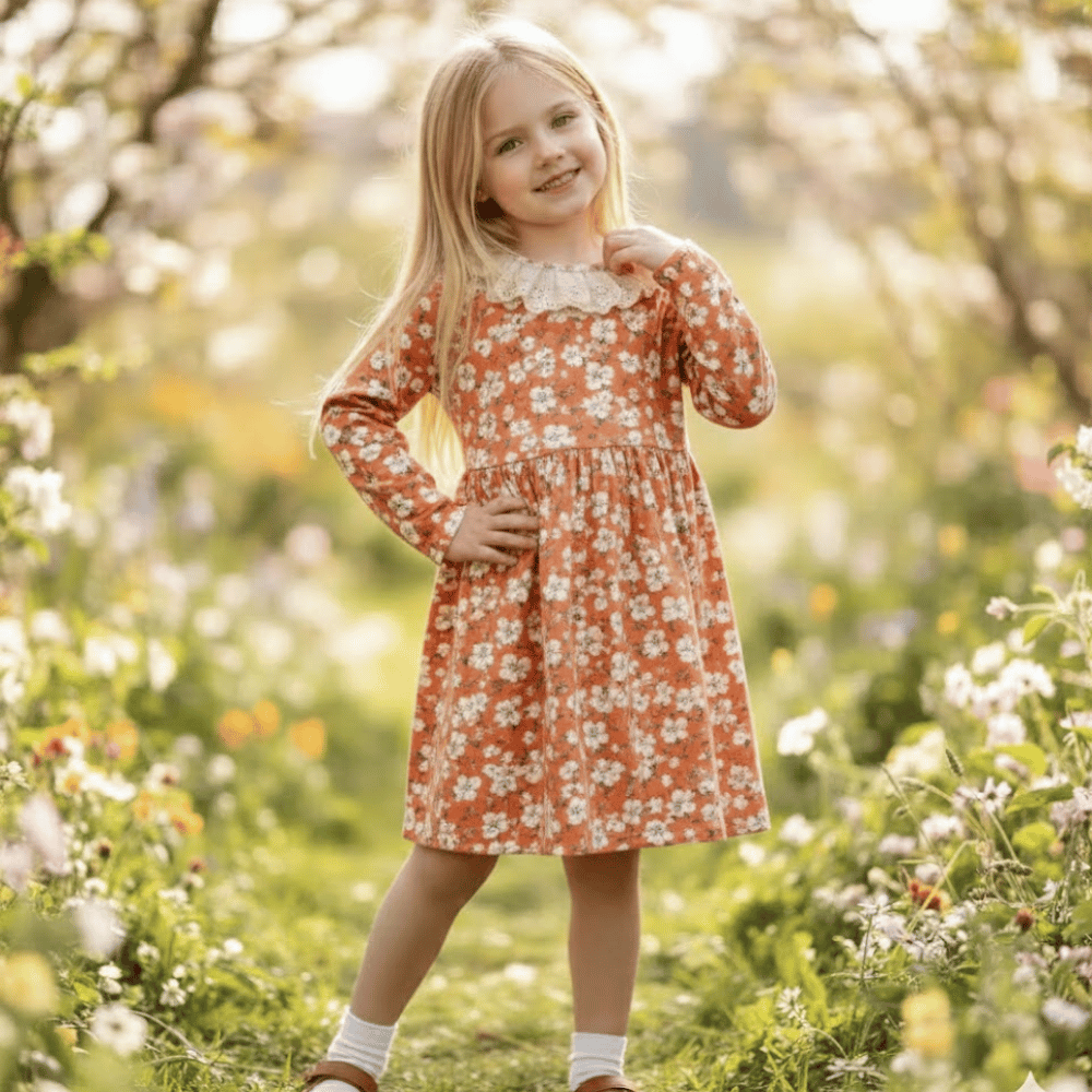 Young girl in a floral dress standing in a garden with blurred background