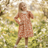Young girl in a floral dress standing in a garden with blurred background