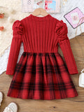 Red ribbed sweater with plaid skirt on a wooden surface
