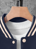 Navy blue varsity jacket with beige accents on a hanger against a gray concrete wall.