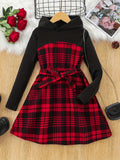 Red and black plaid dress with black long-sleeve top on a wooden surface.