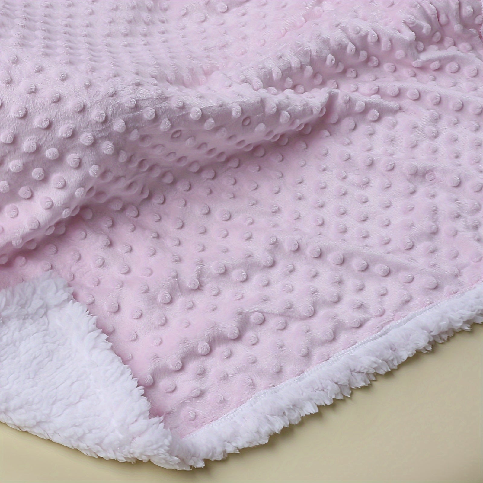 Pink textured blanket with white border on a beige background