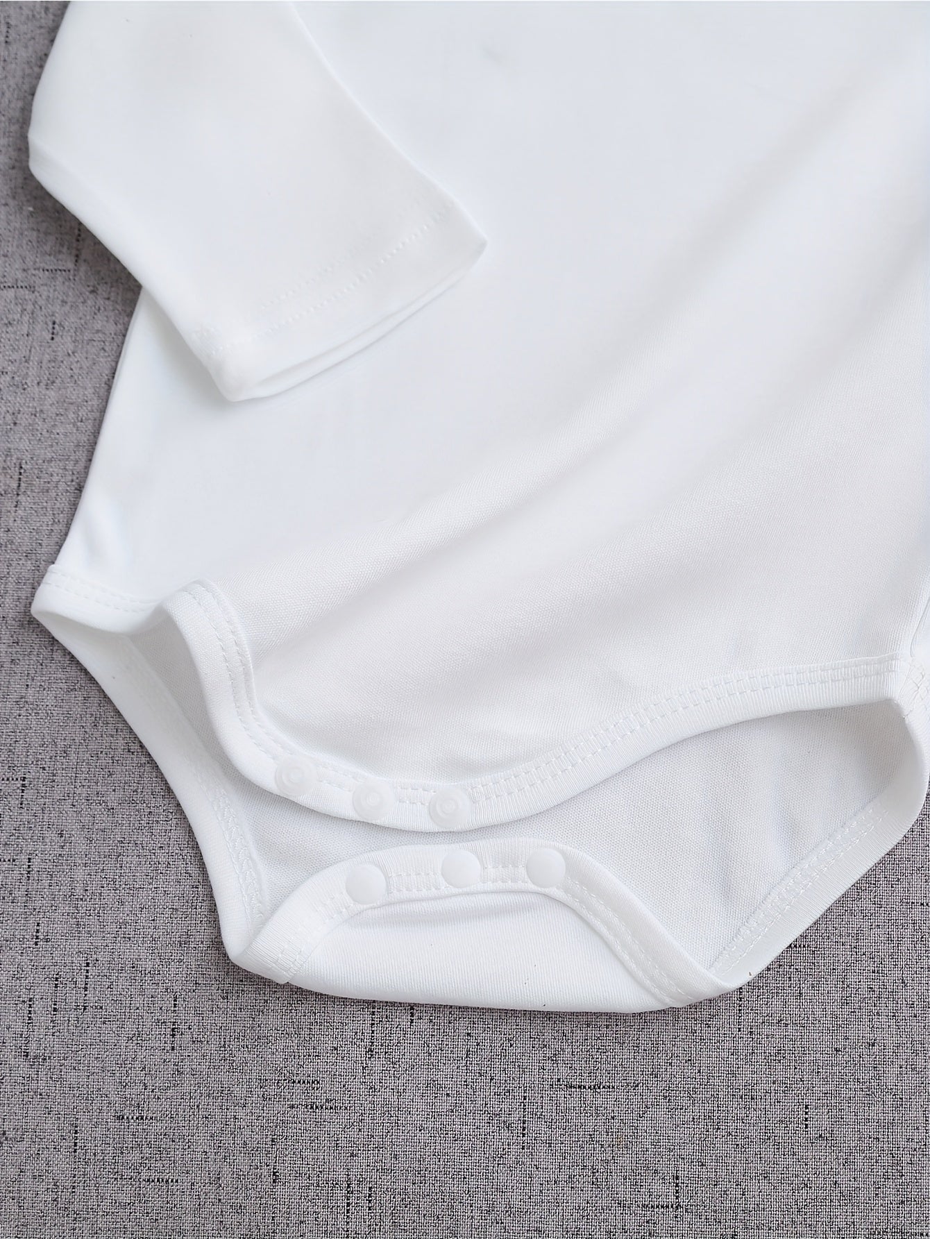 White baby onesie on a gray textured surface