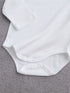 White baby onesie on a gray textured surface