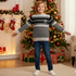 Child wearing a striped sweater in a festive living room with Christmas decorations.