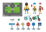 Toy set with road mat, figures, bicycles, and traffic signs on a white background